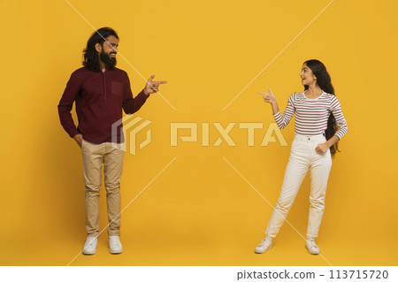 Man and woman pointing each other on yellow background 113715720