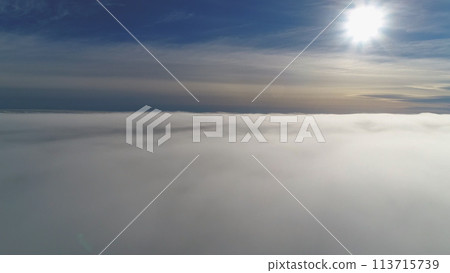 Sun through fog. Antarctica aerial drone view flight. White bright polar sun disk appears in the clear blue sky, from dense grey hazy covering Antarctic continent. Amazing. Sun through fog. Antarctica aerial drone view flight. White bright polar sun disk appears in the clear blue sky, from dense grey hazy covering Antarctic continent. Amazing. 113715739