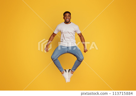 Positive african american guy jumping and clapping his legs 113715884