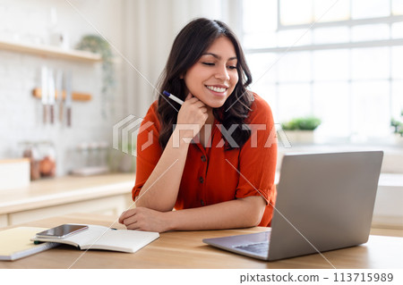 Smiling arab woman working on laptop at home 113715989