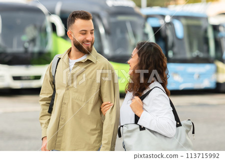 Smiling young couple walking with bags at bus station and chatting 113715992