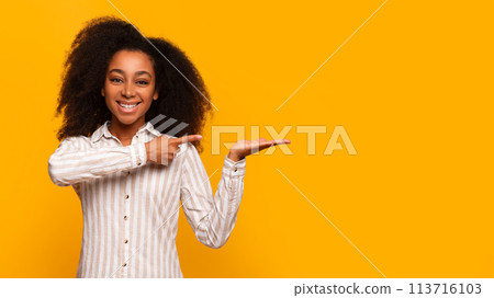 Young woman presenting with hand gesture on yellow background Young woman presenting with hand gesture on yellow background 113716103