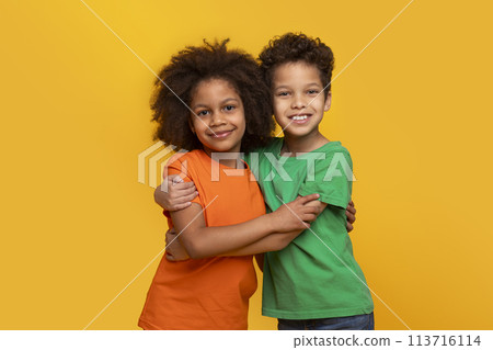 African American siblings hugging smiling on yellow background 113716114