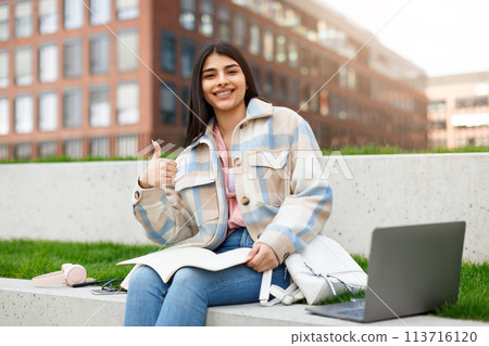 Smiling student with laptop giving thumbs up Smiling student with laptop giving thumbs up 113716120