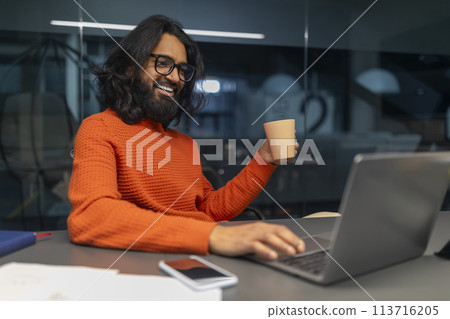 Man holding cup while working on laptop 113716205