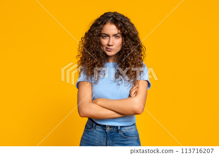 Skeptical woman with arms crossed on yellow 113716207