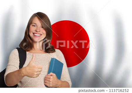 Positive woman student showing thumb up against Japanese flag background. Travel 113716252
