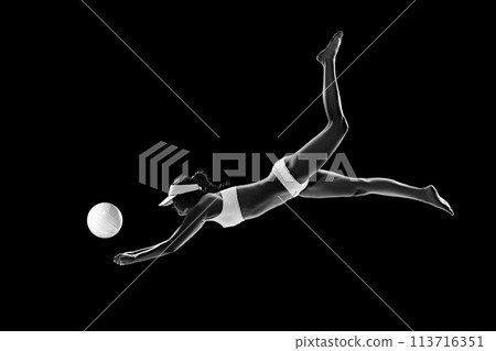 Athletic woman, volleyball player diving for ball in mid-air to make pass against black background. Monochrome filter. Athletic woman, volleyball player diving for ball in mid-air to make pass against black background. Monochrome filter. 113716351