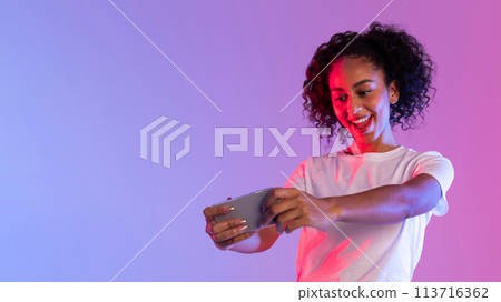 Woman playing game on smartphone in neon light Woman playing game on smartphone in neon light 113716362