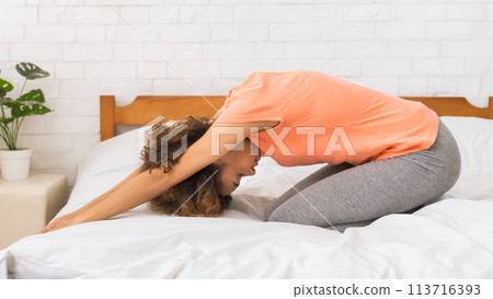 Girl doing yoga exercise on bed in the morning 113716393