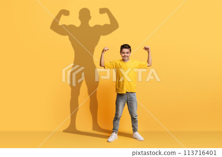 An enthusiastic young boy in a yellow shirt flexes his arms with confidence An enthusiastic young boy in a yellow shirt flexes his arms with confidence 113716401