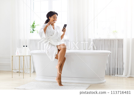 Woman relaxing in bathroom with smartphone at home 113716481