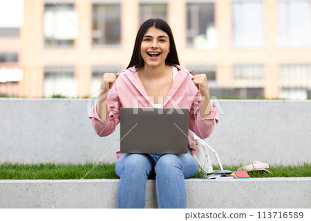 Excited young lady celebrating success with laptop Excited young lady celebrating success with laptop 113716589
