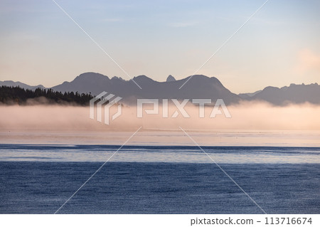 Misty lake framed by mountains, creating a serene natural landscape 113716674