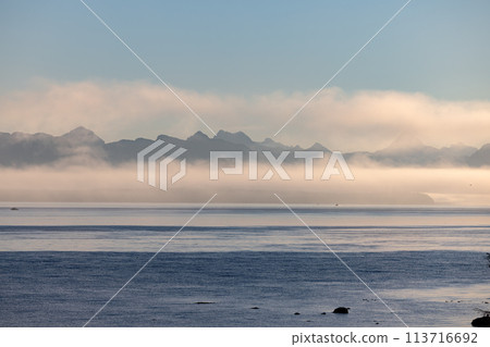 Misty lake framed by mountains, creating a serene natural landscape 113716692