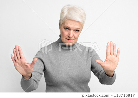 Senior woman with arms raised in a stop sign 113716917