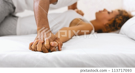 Close-up of couple holding hands on bed 113717093