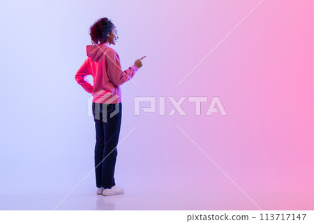 Rear view of woman pressing invisible button on gradient backdrop Rear view of woman pressing invisible button on gradient backdrop 113717147
