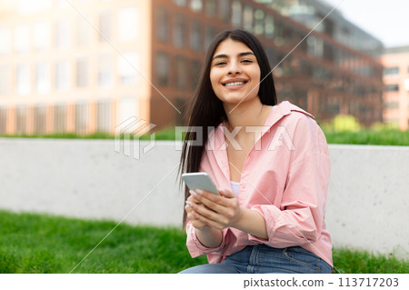 Smiling young girl texting on her smartphone Smiling young girl texting on her smartphone 113717203