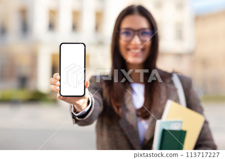 Smiling student showing smartphone screen at university campus Smiling student showing smartphone screen at university campus 113717227