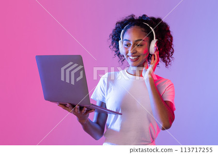 Happy woman using laptop and headphones Happy woman using laptop and headphones 113717255