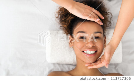 African-american woman enjoying face massage at beauty salon 113717306
