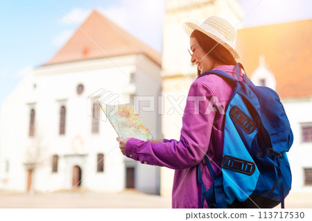 Woman holding map in square with sunlight flares Woman holding map in square with sunlight flares 113717530