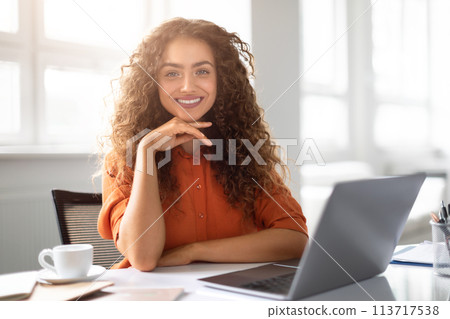 Smiling woman with laptop at a sunny office 113717538