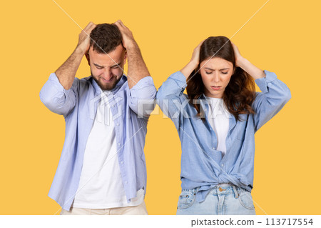 Stressed man and woman holding heads 113717554