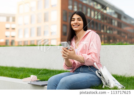 Girl using smartphone with laptop and headphones 113717625