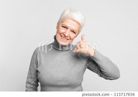Smiling senior woman gesturing call me sign Smiling senior woman gesturing call me sign 113717656