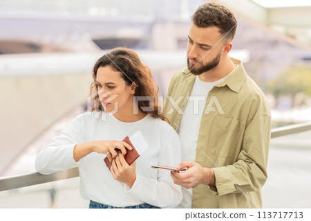 Man and woman looking concerned while examining tickets or documents in airport Man and woman looking concerned while examining tickets or documents in airport 113717713