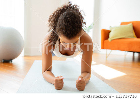 Woman maintaining core strength with elbow plank on mat indoor Woman maintaining core strength with elbow plank on mat indoor 113717716
