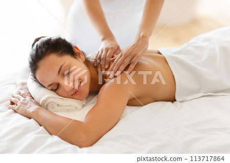 Caucasian lady with eyes closed experiences therapeutic back massage indoors 113717864