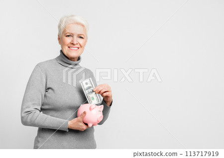 Elderly woman saving in a piggy bank Elderly woman saving in a piggy bank 113717919