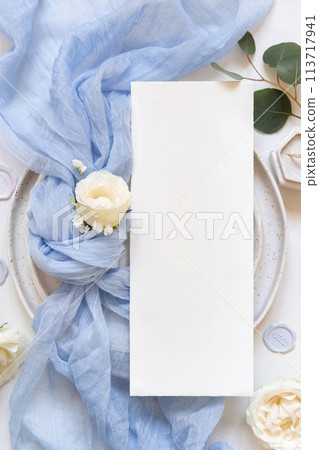 Card near blue tulle fabric knot and cream roses on plates top view copy space, wedding mockup Card near blue tulle fabric knot and cream roses on plates top view copy space, wedding mockup 113717941