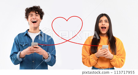 An exuberant young man in a denim jacket laughs holding his phone while an astonished young woman in an orange sweatshirt An exuberant young man in a denim jacket laughs holding his phone while an astonished young woman in an orange sweatshirt 113717955