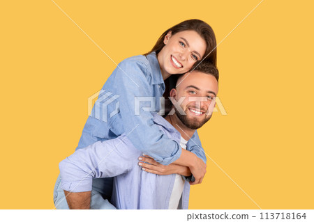 Woman piggybacking on man's back on yellow Woman piggybacking on man's back on yellow 113718164
