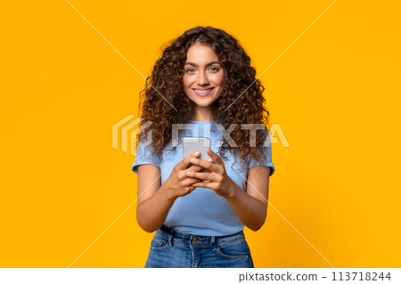 Content woman using a smartphone on yellow Content woman using a smartphone on yellow 113718244