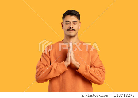 Man with moustache in prayer pose on orange 113718273