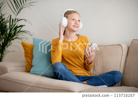 Smiling Teen Girl Enjoying Music on Headphones at Home Smiling Teen Girl Enjoying Music on Headphones at Home 113718287
