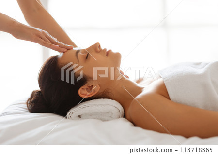 Side view of therapist making head massage for lady indoors Side view of therapist making head massage for lady indoors 113718365