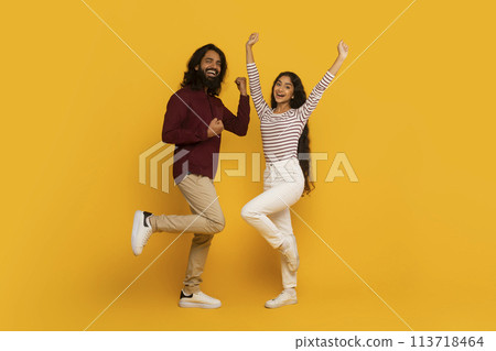 Man and woman jumping with raised arms on yellow 113718464