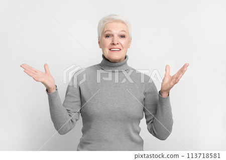 Elderly woman shrugging with confusion on grey background Elderly woman shrugging with confusion on grey background 113718581