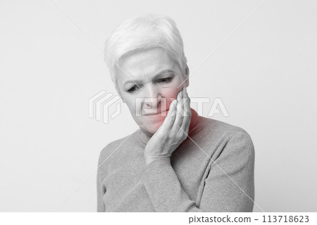 Elderly woman experiencing jaw discomfort, black and white photo Elderly woman experiencing jaw discomfort, black and white photo 113718623