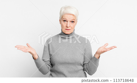 Perplexed senior woman with hands open on grey background 113718648