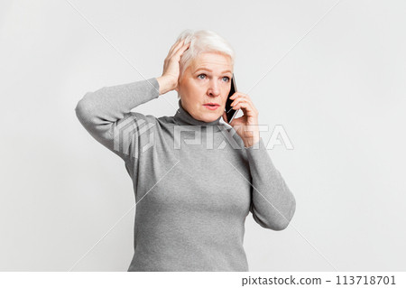 Senior woman puzzled while talking on the phone 113718701
