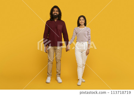 Couple holding hands against yellow wall 113718719