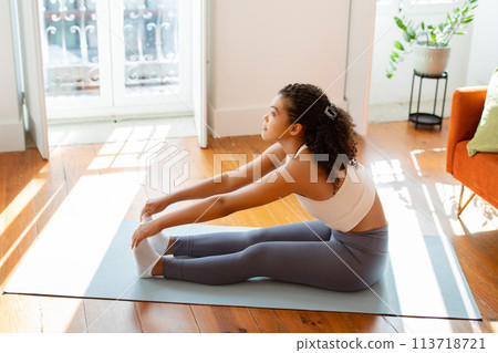 Sporty young lady stretching touching her toes on mat indoors 113718721