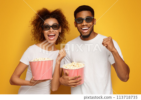 Laughing couple in 3d glasses holding buckets of popcorn Laughing couple in 3d glasses holding buckets of popcorn 113718735